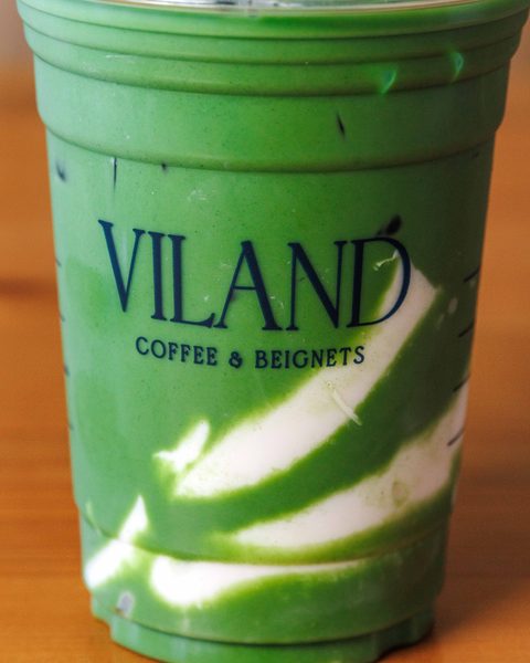 Cận cảnh ly matcha latte đá trong cốc ViLand, đặt trên bàn gỗ.