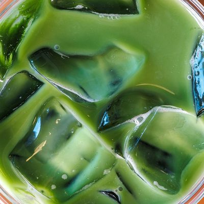 Nhìn từ trên xuống ly matcha latte đá, những viên đá nổi trong sữa xanh nhạt.