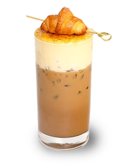 Cà phê đá trong ly cao, phủ lớp kem dày với mặt đường khò cháy, một chiếc croissant nhỏ xiên que đặt ngang miệng ly